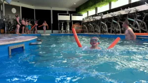 Un enfant dans la piscine avec des lunettes de plongée et une frite orange