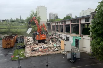 Pelleteuse sur un tas de gravas près du gymnase en destruction