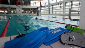 Paire de palme devant le bassin d'une piscine avec un nageur