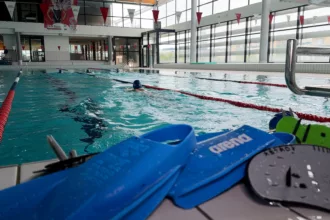 Paire de palme devant le bassin d'une piscine avec un nageur
