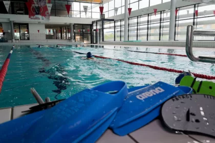 Paire de palme devant le bassin d'une piscine avec un nageur