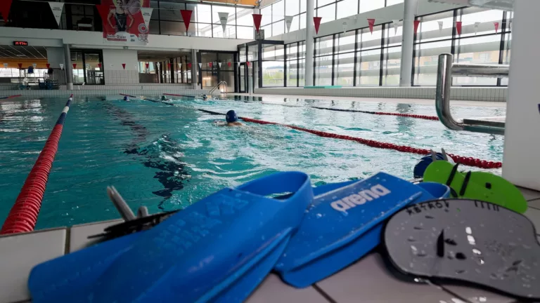 Paire de palme devant le bassin d'une piscine avec un nageur