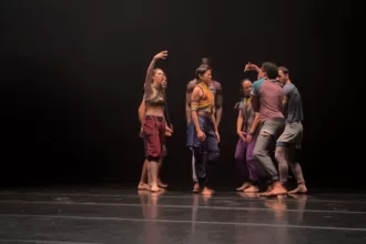 Sept danseurs sur une scène de spectacle noire