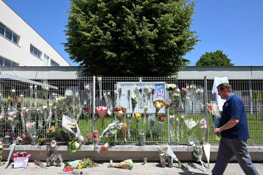 A man walks past flowers on the fence of Francoise Dolto middle school in Nogent on June 11, 2025, a day after a secondary school pupil was arrested after killing a 31-year-old school assistant with a knife during a bag search. (Photo by FRANCOIS NASCIMBENI / AFP)